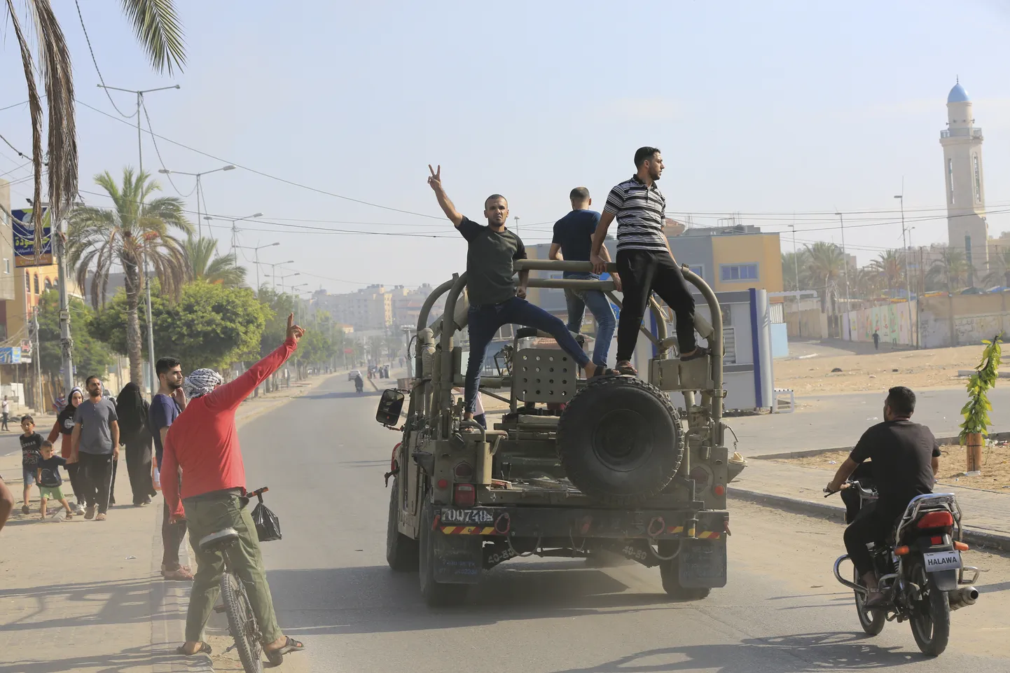 Палестинцы едут на израильском военном автомобиле, захваченном армейской базой, захваченной боевиками ХАМАС, возле забора сектора Газа, в городе Газа, суббота, 7 октября 2023 года. (AP Photo/Abed Abu Reash) DV221