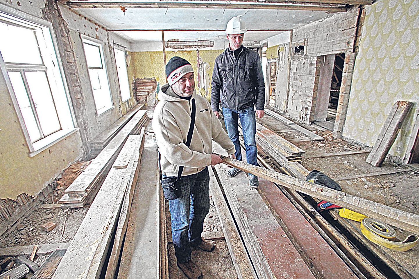 Maja taastamise projektijuht Ain Sinikas (vasakul) ja ehitusjärelevalve tegija Andrus Mutli uurivad ligi kolmekümne sentimeetri laiusi tappühendusega põrandalaudu, mis on plaanis kõik uuesti maha panna.