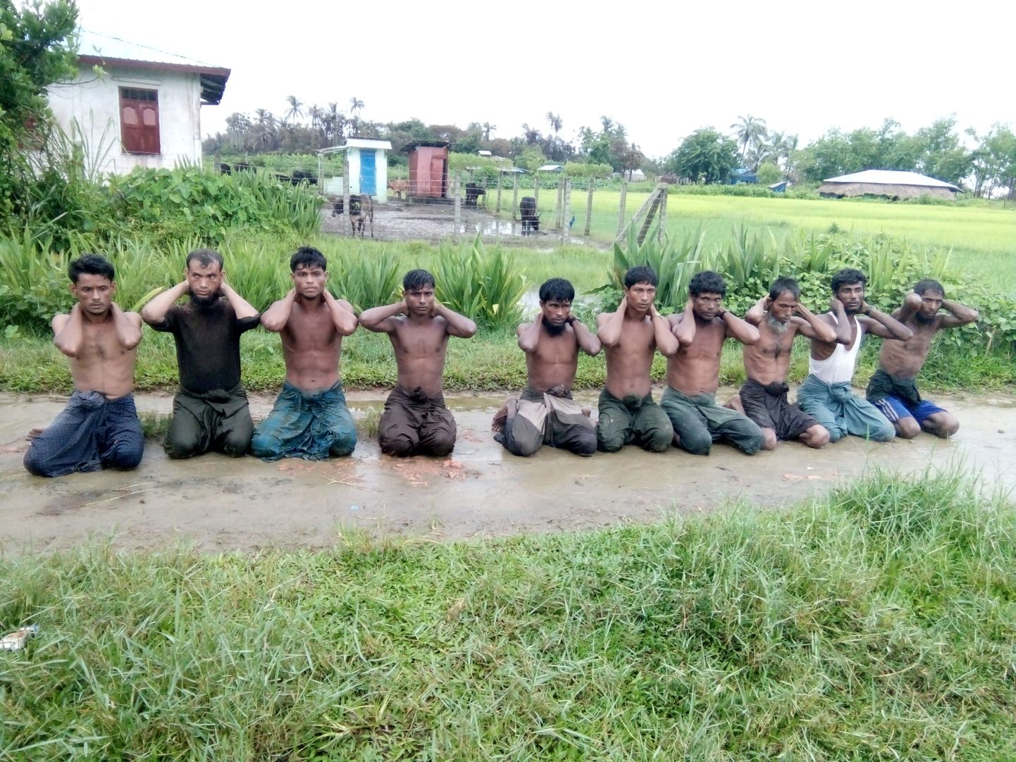 Rohingjad Birmas käed kuklal põlvitamas.