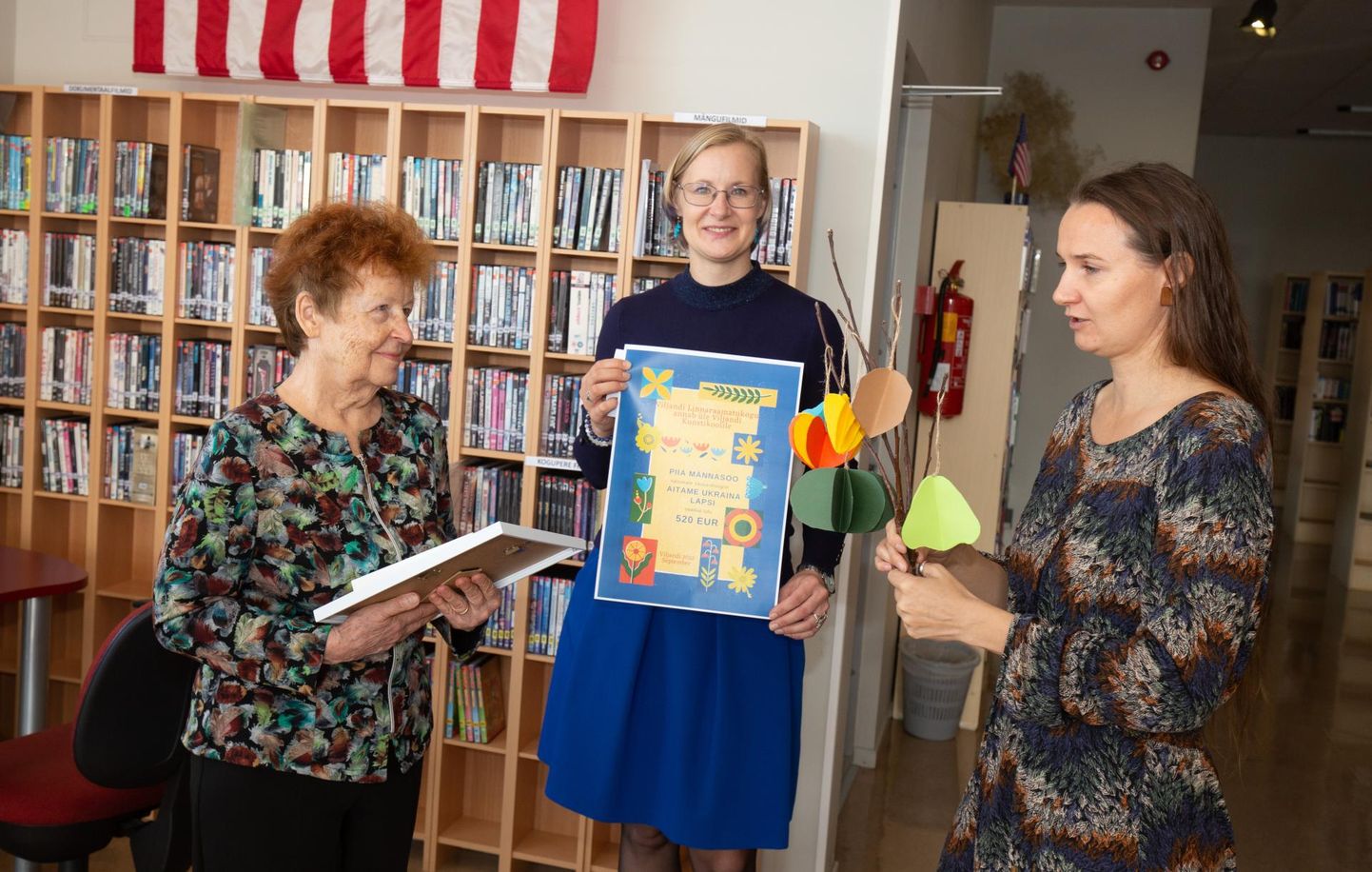 Kaisuloomad heegeldanud Piia Männasoo (vasakul) sai raamatukogu direktorilt Reet Lubilt tänukirja ning kunstikooli direktorilt Laineli Parrestilt lillekimbu.