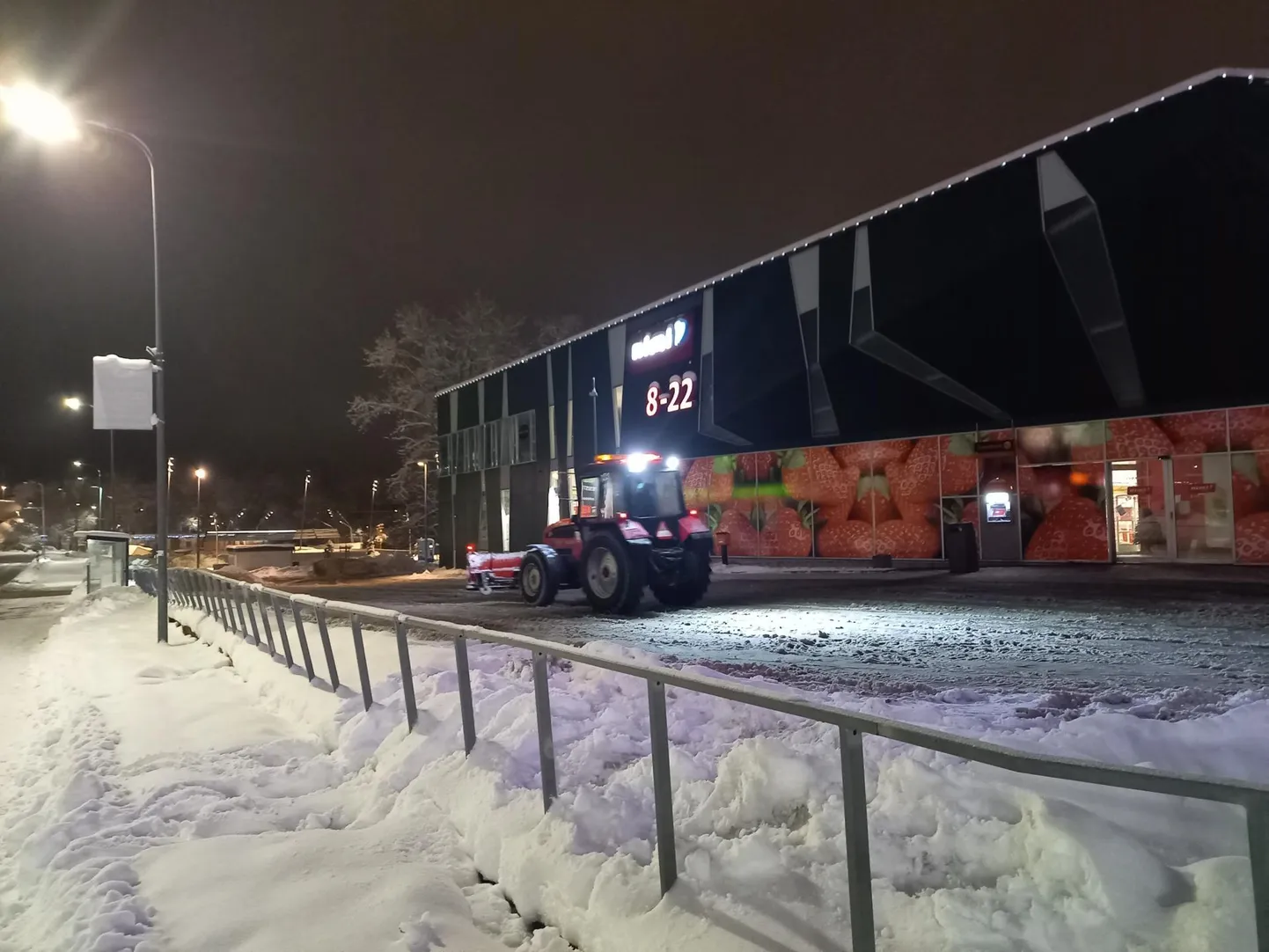 Traktor kauplusehoone parklas lund lükkamas.
