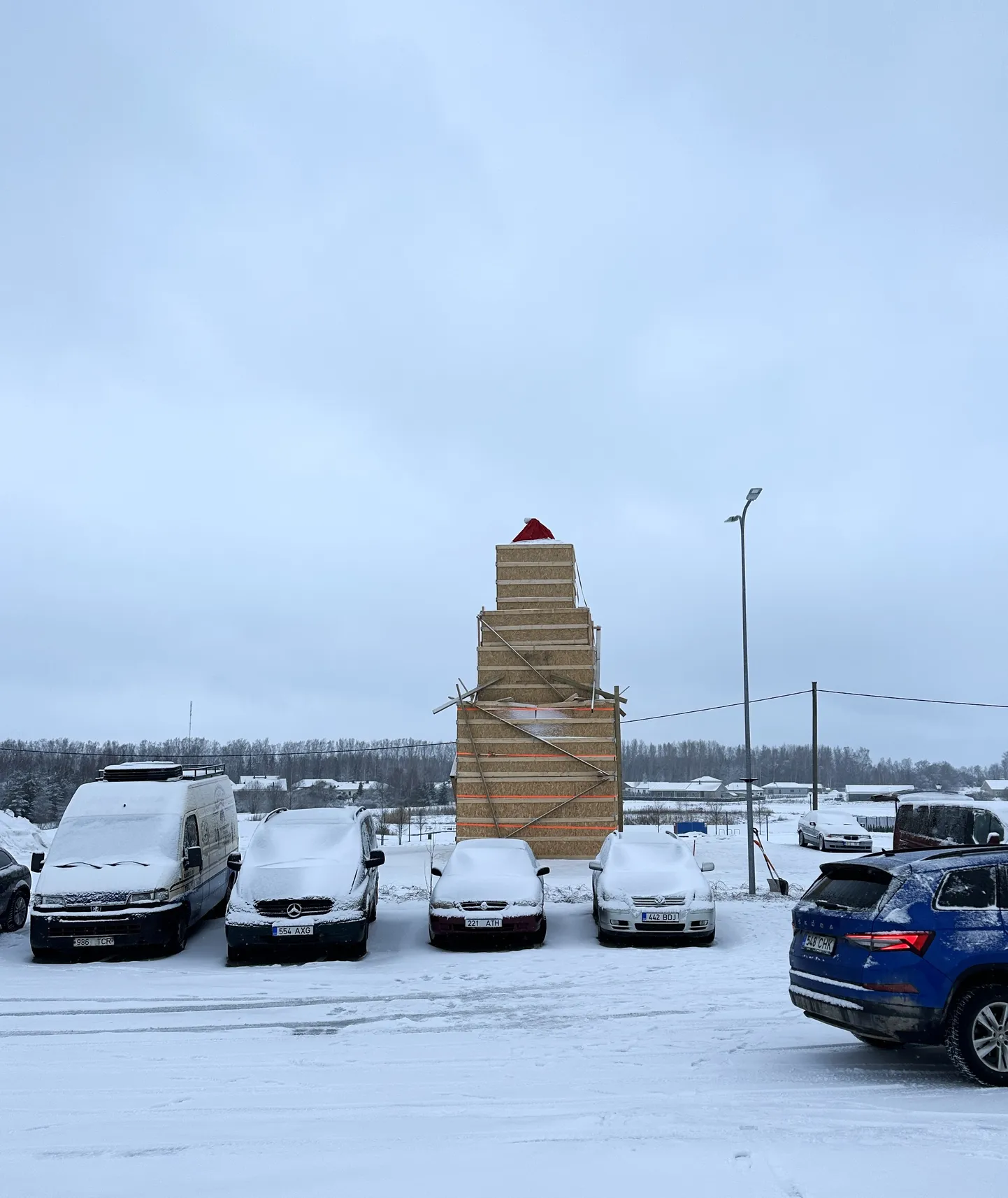 Lumememm kolmes kastis, külma tuule eest pakub kaitset punane müts.