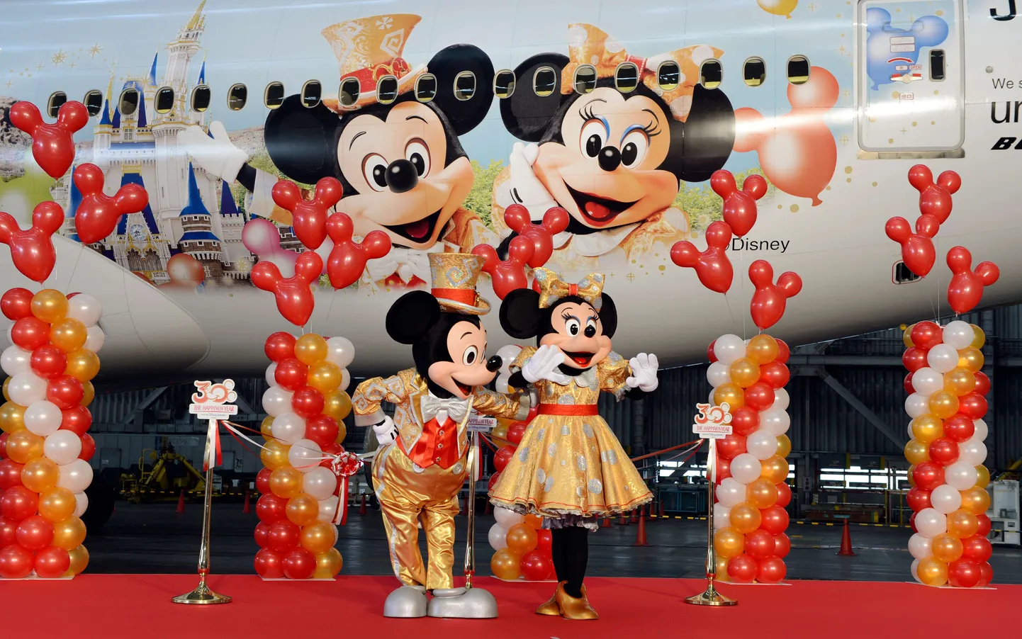Miki-Hiir ja Minni-Hiir seisavad Disney tegelaskujudega dekoreeritud reisilennuki Boeing 777-200 juures.