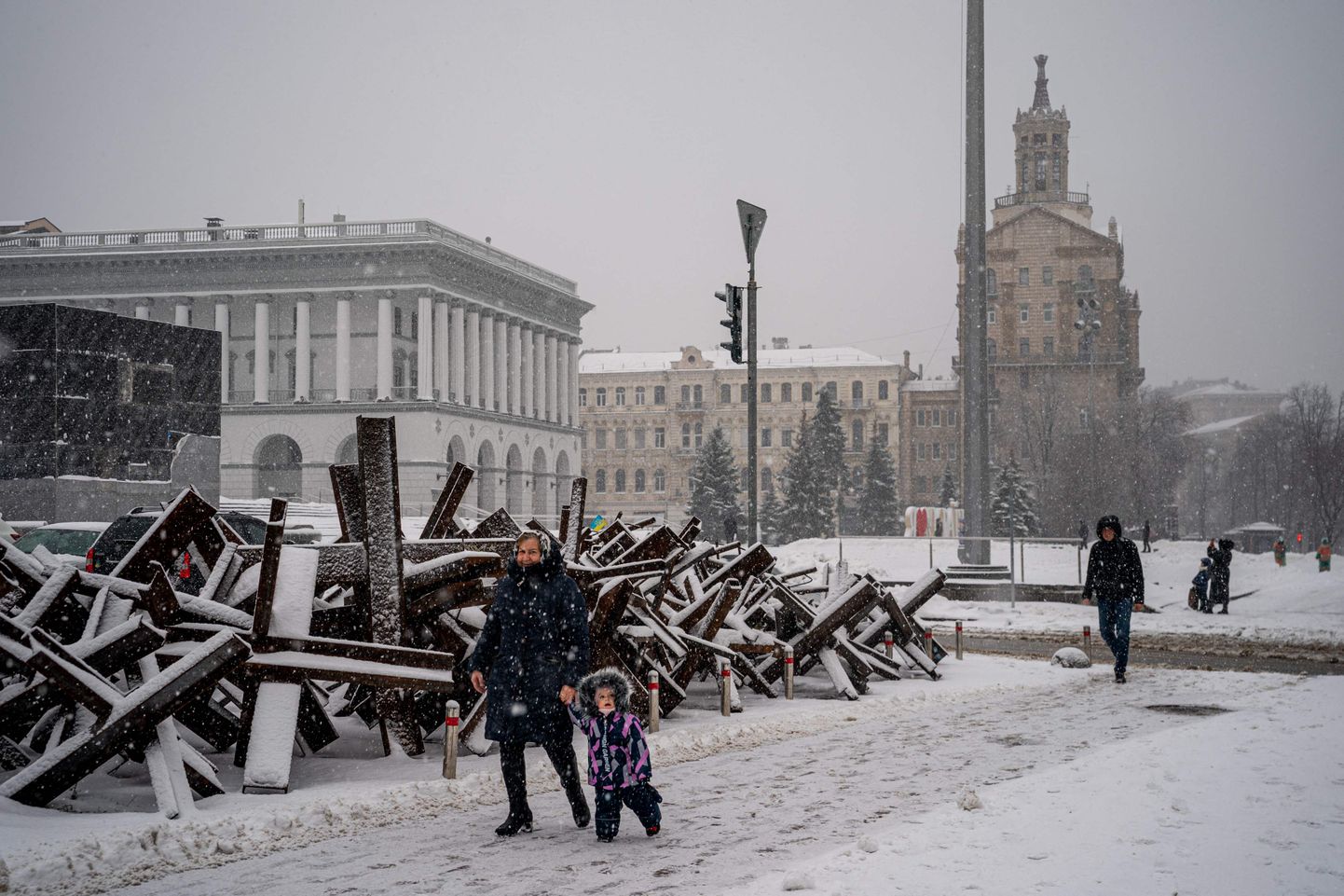 Naine ja laps kõnnivad mööda lumega kaetud tankitõrje siilidest Ukraina pealinnas Kiievis.