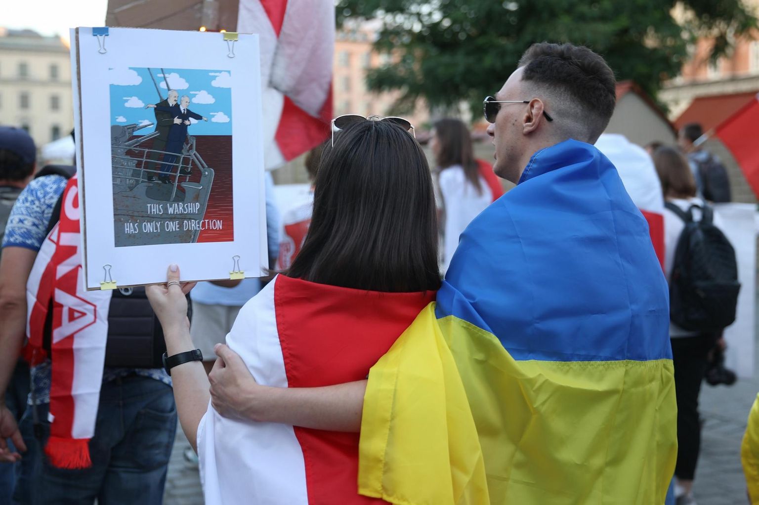 Valgevene ja Ukraina lippu mähitud paar augustis Poolas Krakówis meeleavaldusel, märkimaks kahe aasta möödumist Valgevene presidendivalimistest, kus Aljaksandr Lukašenka kindlustas endale pettusega võimule jäämise ja surus vägivaldselt maha vallandunud meeleavaldused. Naine hoiab käes joonistust Lukašenkast ja Venemaa presidendist Vladimir Putinist filmist «Titanic» tuttavas poosis, juures kiri «Sellel sõjalaeval on vaid üks suund».