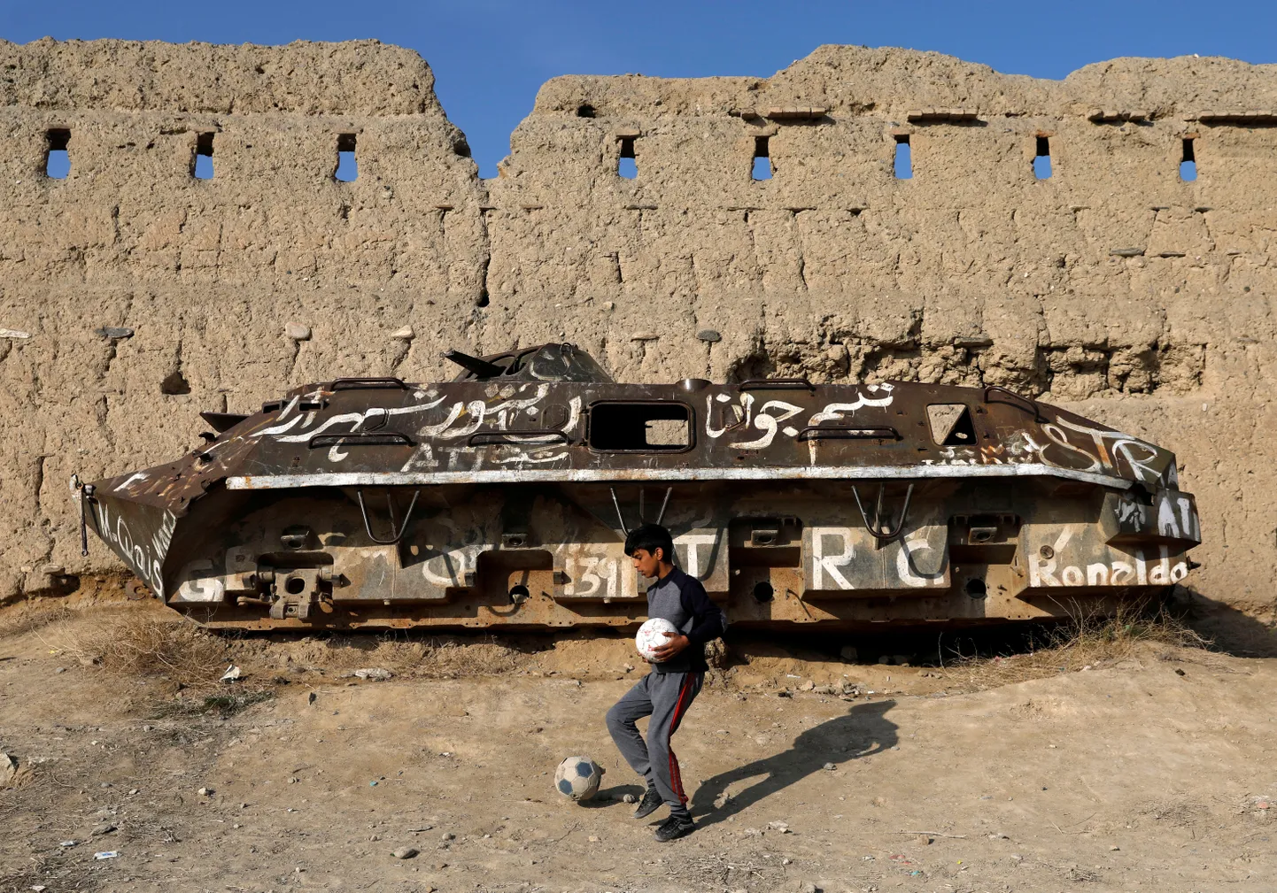 Afgaani poiss mängib jalgpalli purustatud soomuki ees 24. veebruar 2020.