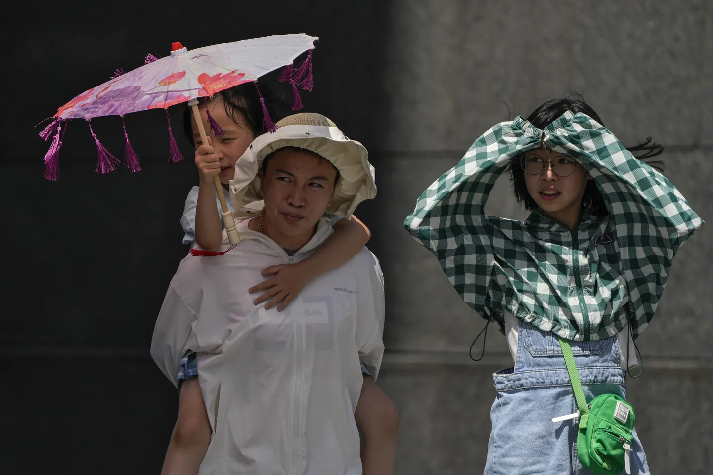 Пекинская семья использует одежду и тень, чтобы защититься от палящего солнца во время нынешней жары, которая достигает 40 градусов по Цельсию.