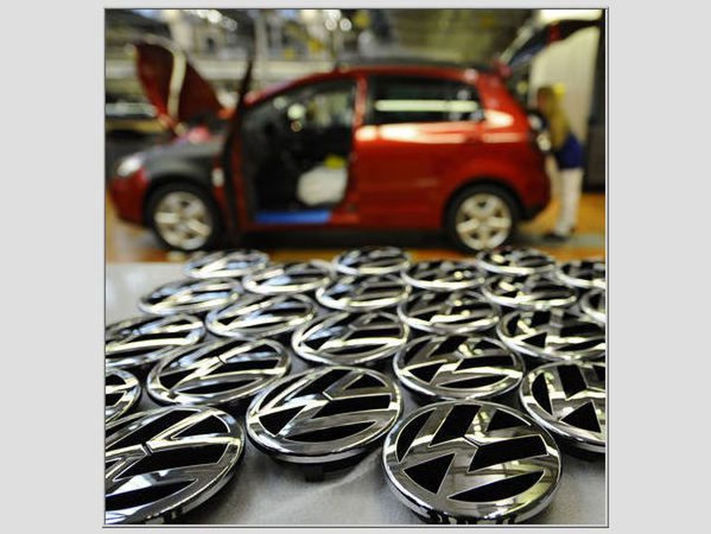 Volkswageni logod lebamas Saksamaal Wolfsburgi tehase põrandal koosteliini kõrval.