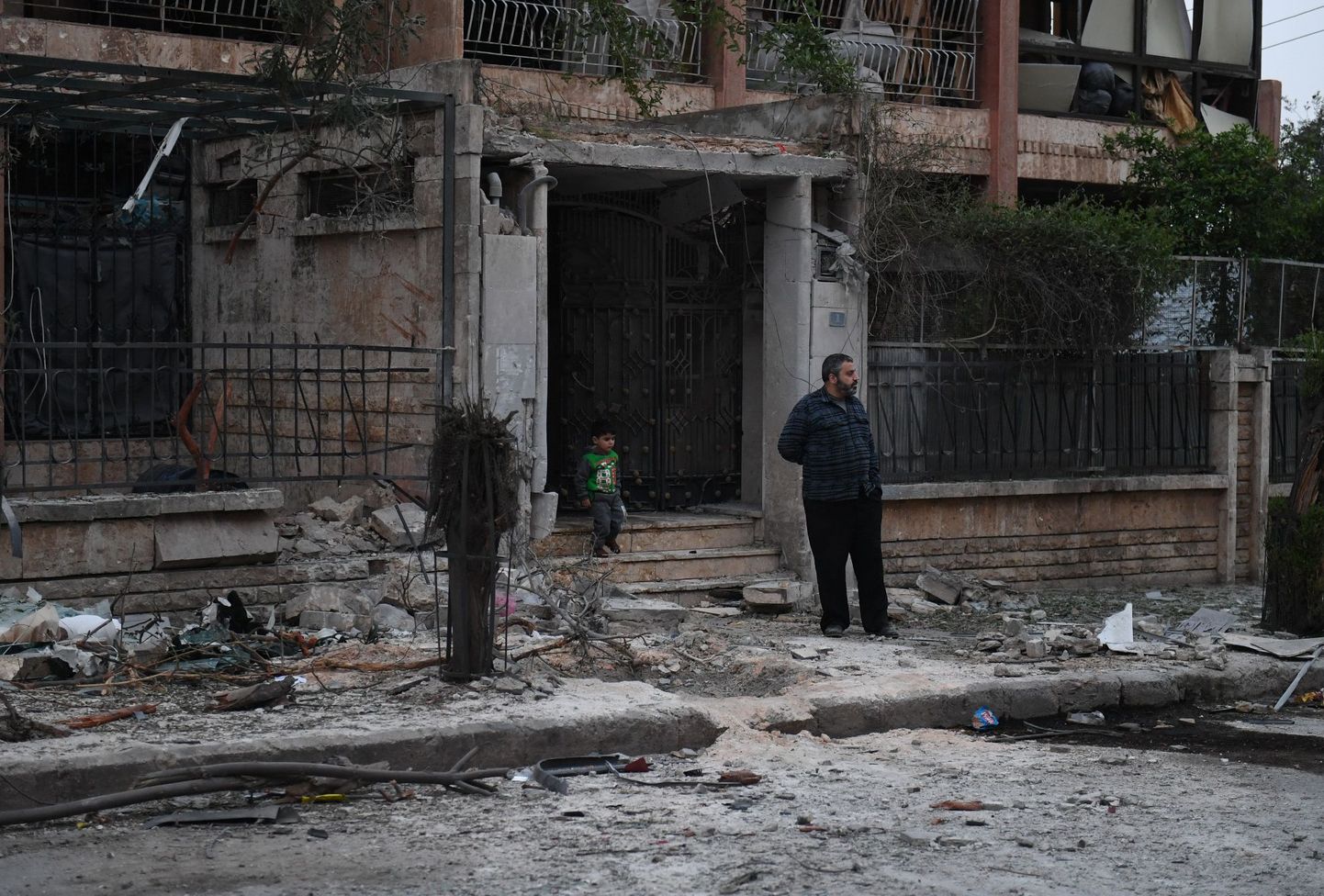 Mees ja laps raketitabamuse saanud maja ees Aleppos.