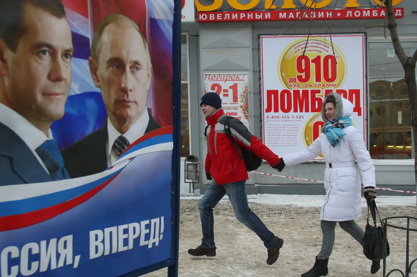 Mees ja naine jalutavad Ivanovo linnas mööda Ühtse Venemaa valimisplakatist, millel president Medvedev ja peaminister Putin ärgitavad Venemaad edasi liikuma.