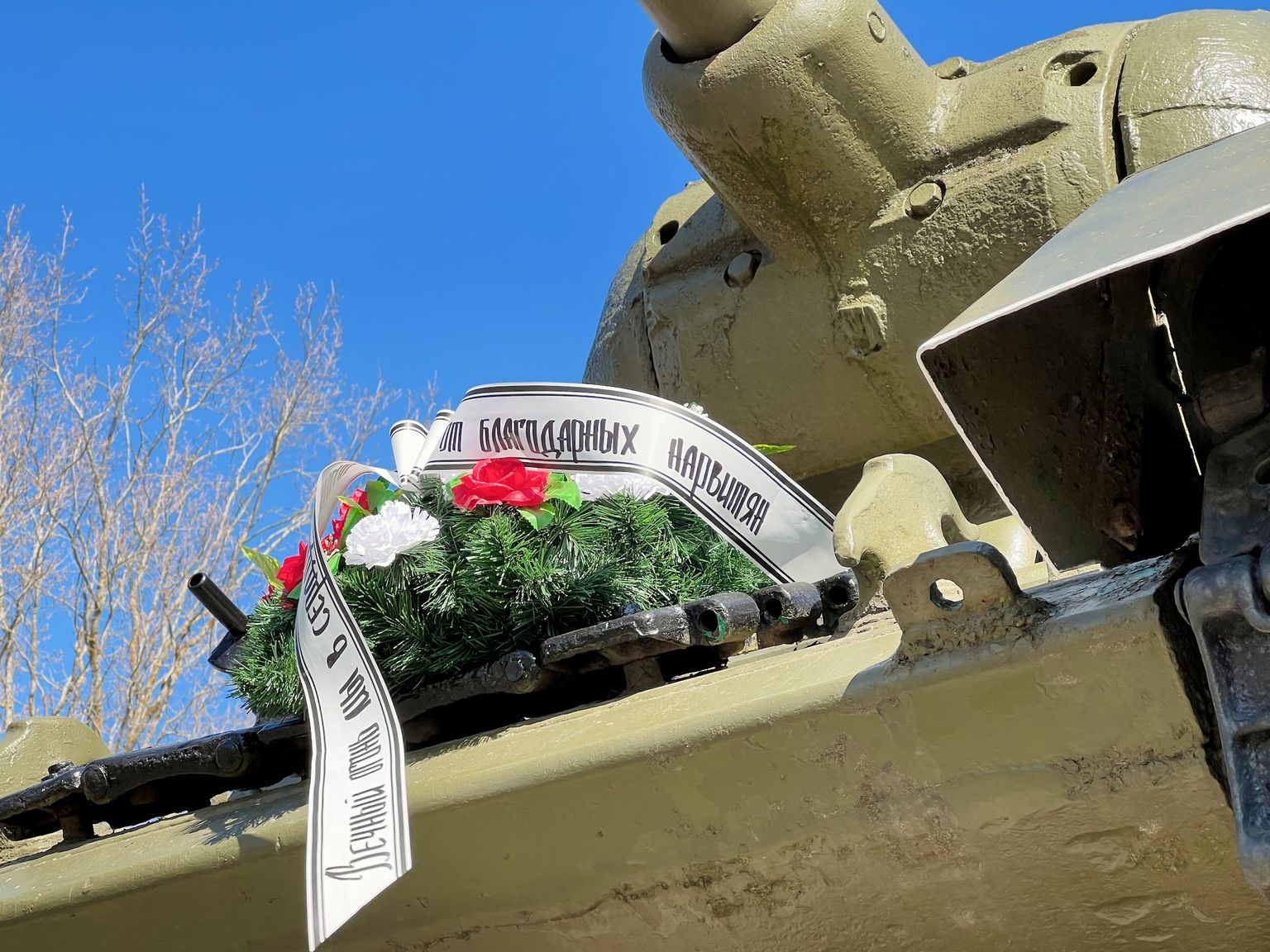 "От благодарных нарвитян" - надпись на венке на броне танка Т-34, стоящем в виде памятника на берегу пограничной реки Нарва.
