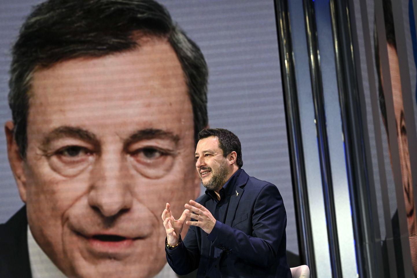 Liiga juht Matteo Salvini kõnelemas Mario Draghi pildi ees.