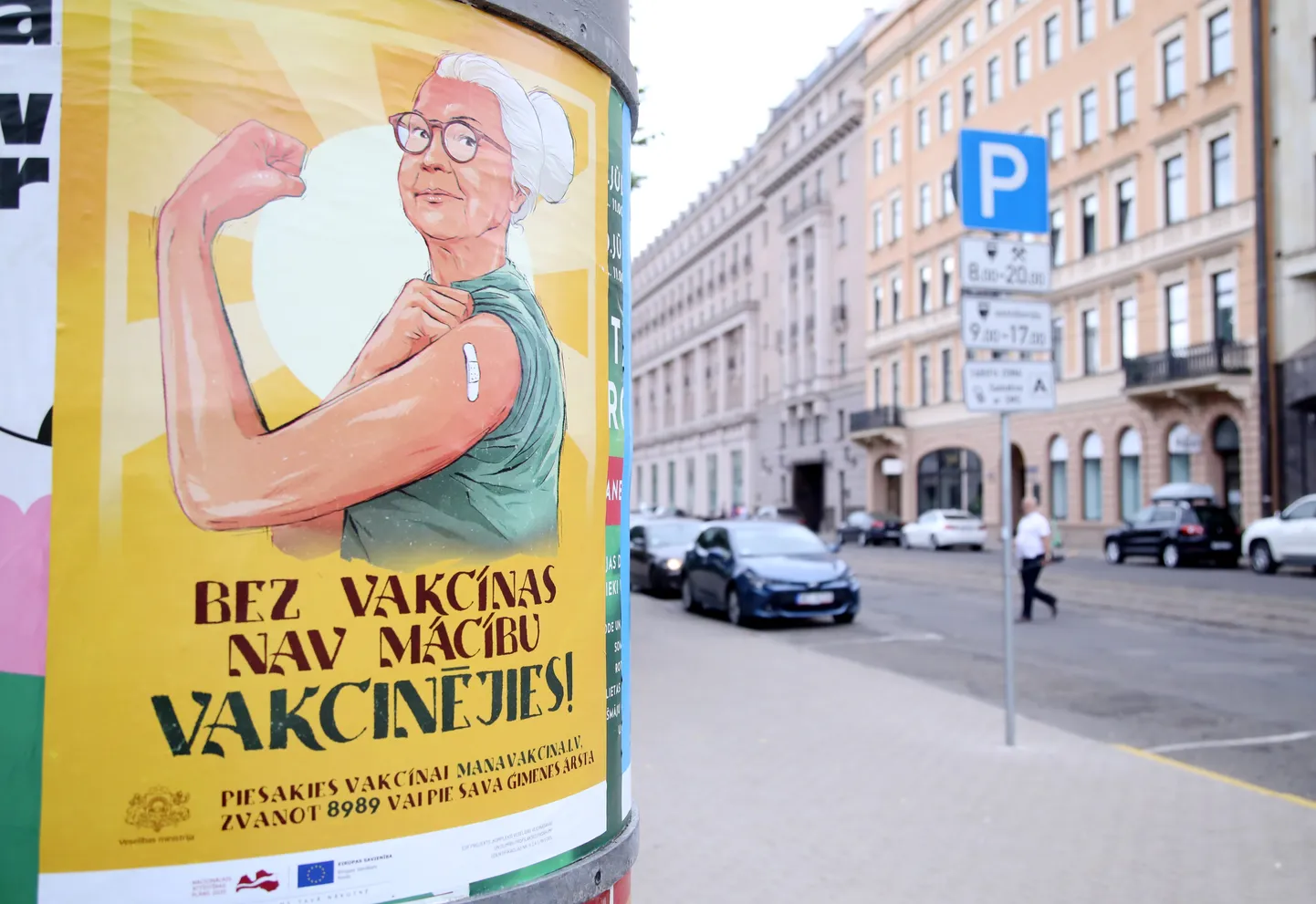 Vakcinācijas pret Covid-19 vides plakāts uz reklāmstaba.