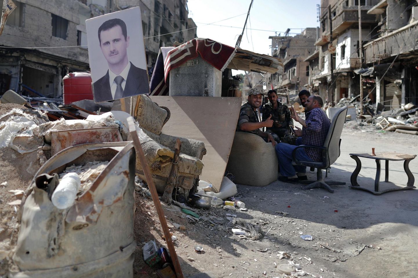 Süüria sõjaväelased Yarmūki põgenikelaagri kontrollpunktis. Varjualuse seinal ilutseb president Bashar al-Assadi pilt.