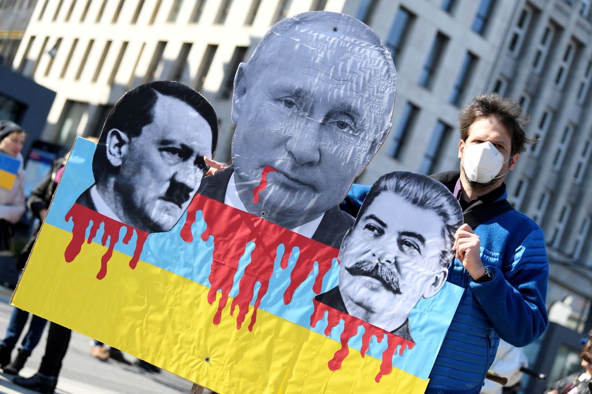 Протестующий во время антивоенной демонстрации в Гамбурге, Германия, 20 марта 2022 года держит плакат с фотографиями президента России Владимира Путина, Адольфа Гитлера и Иосифа Сталина.