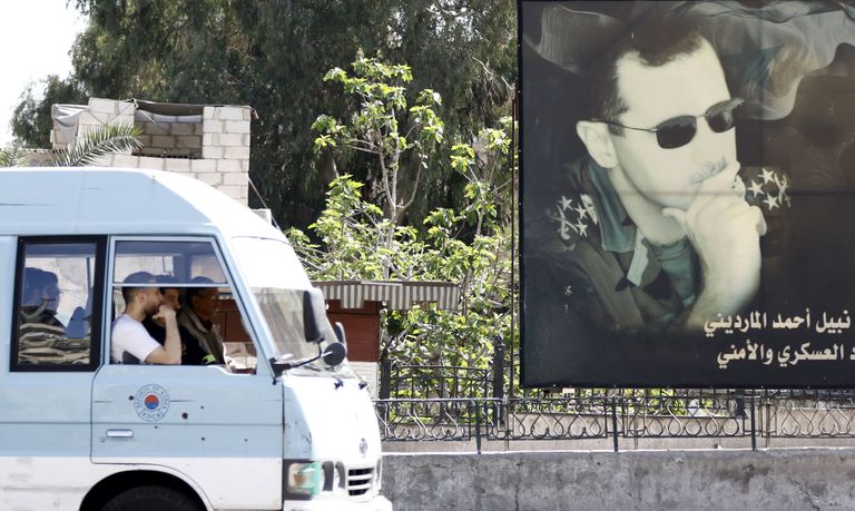 A minivan drives past a portrait of Syrian President Bashar al-Assad in Damascus on April 7, 2017.
US forces fired a barrage of cruise missiles at a Syrian airbase in response to what President Donald Trump called a "barbaric" chemical attack he blamed on the Damascus regime. / AFP PHOTO / Louai Beshara