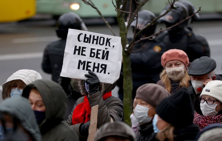 Белорусские пенсионеры идут за милицией во время митинга в Минске 30 ноября 2020 года.