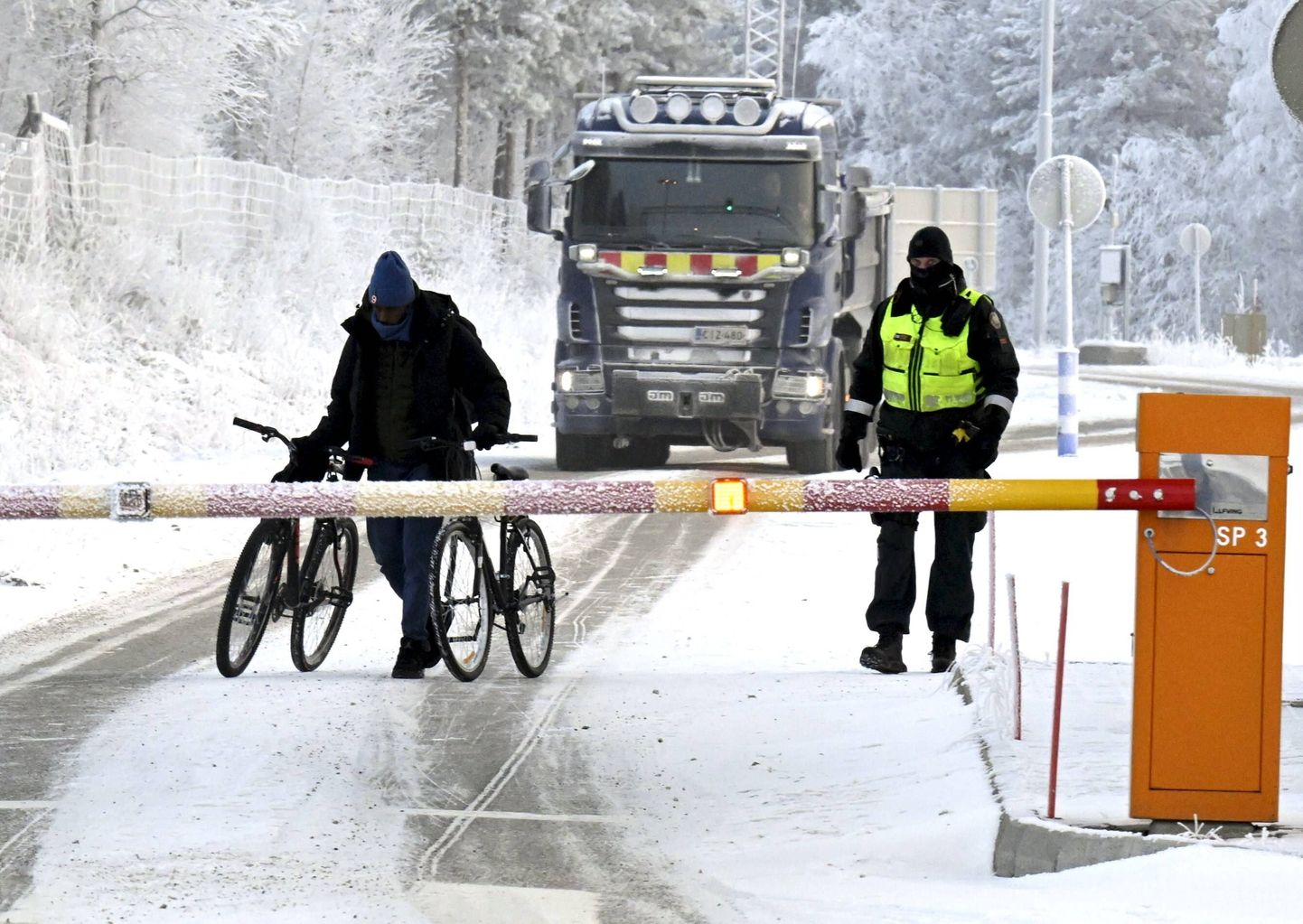Финский пограничник и мигрант с двумя велосипедами на международном пограничном переходе в Салле, который пока открыт для автомобильного сообщения с Россией. Лапландия, вторник, 21 ноября 2023 года.