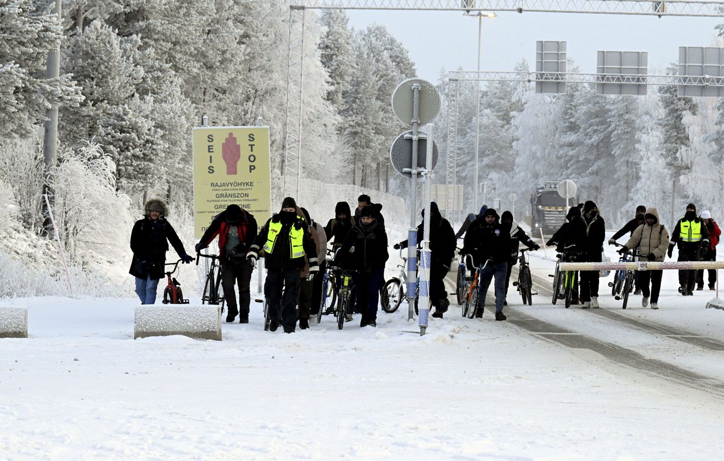 Финские пограничники и мигранты с велосипедами идут по пограничному переходу между Финляндией и Россией, в Салле, Лапландия, Финляндия, 21 ноября 2023 года.