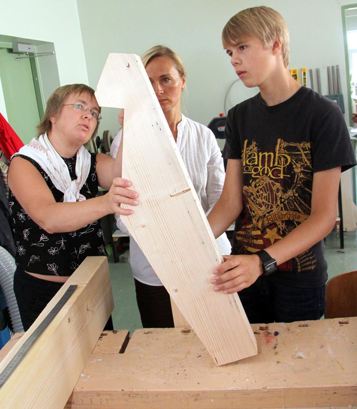Kandlevalmistamise laagris osalejad Erko Elblaus (paremal), Elo Koprek ja Anneli Kala puupakust välja lõigatud väikekandle kuju uurimas.