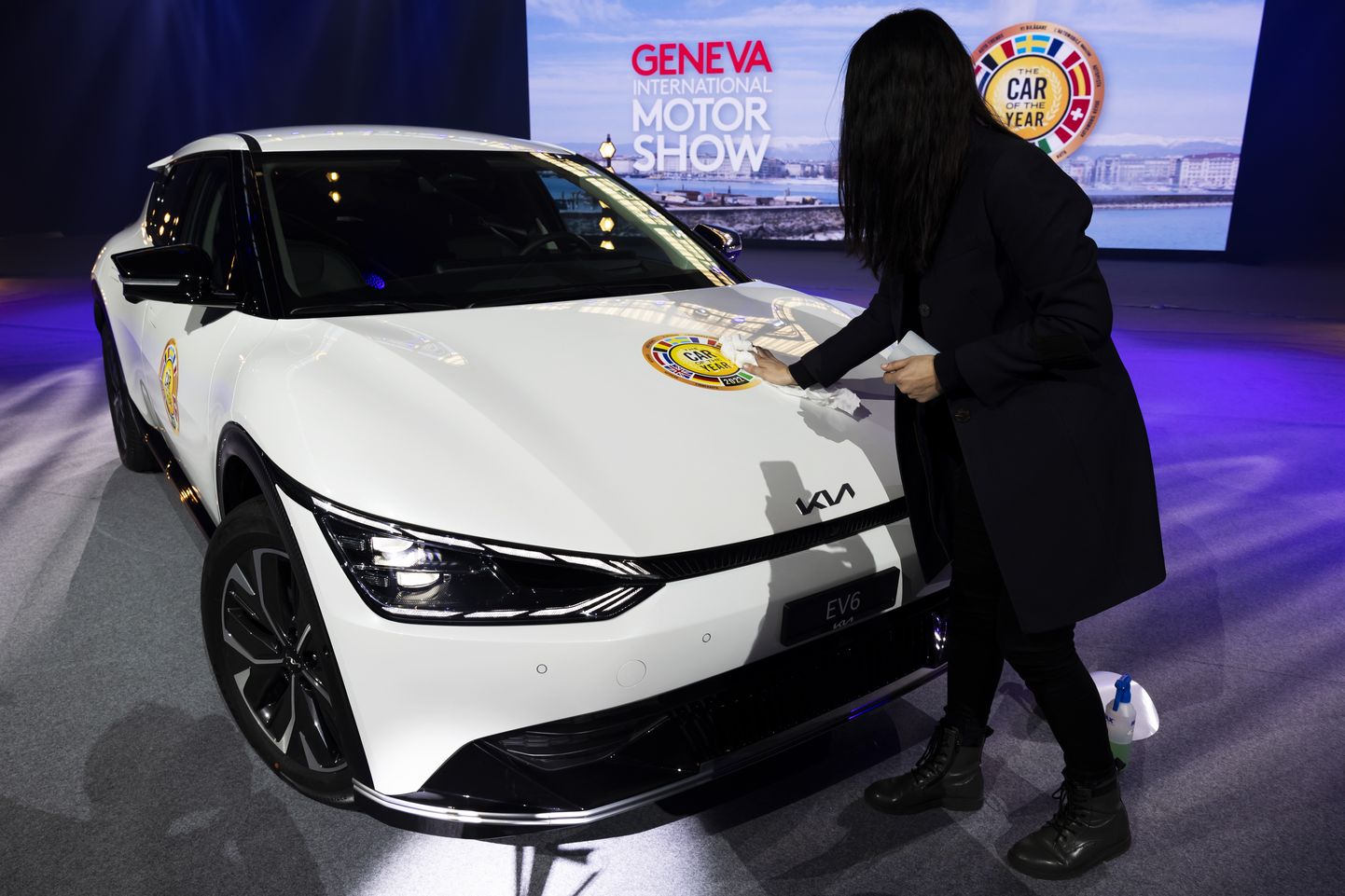 Naisterahvas 28. veebruaril Genfis Kia EV6 kapotil «aasta auto» kleepsu poleerimas.