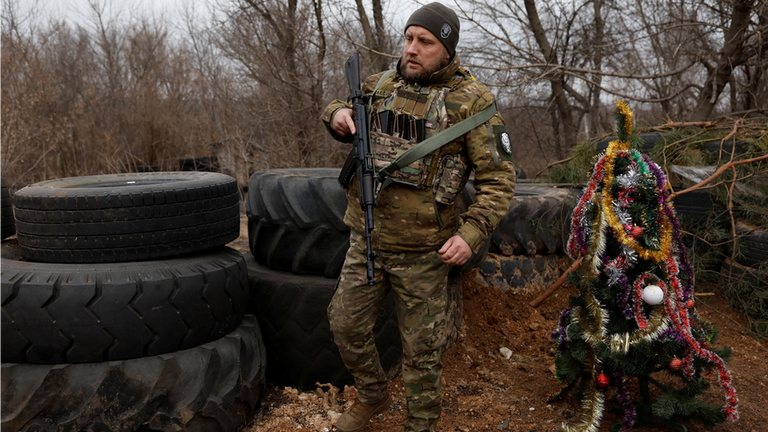Украинский военнослужащий из полка спецназа МВД "Днепр-1" рядом с украшенной рождественской елкой на линии фронта в районе Бахмута