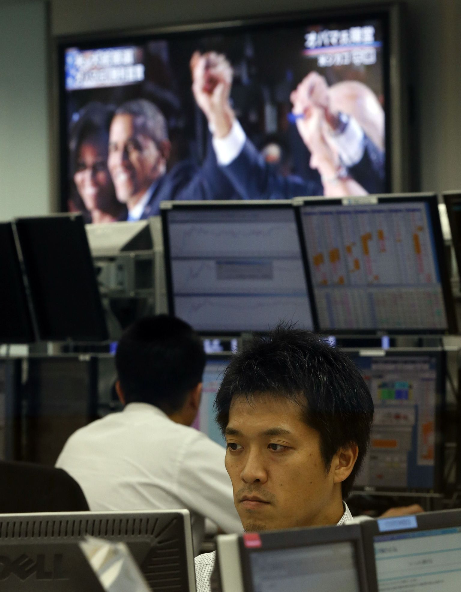 Valuutakaupleja Tokios jälgimas monitori samal ajal kui telerist näidatakse Barack Obama juubeldamist valimisvõidu puhul.