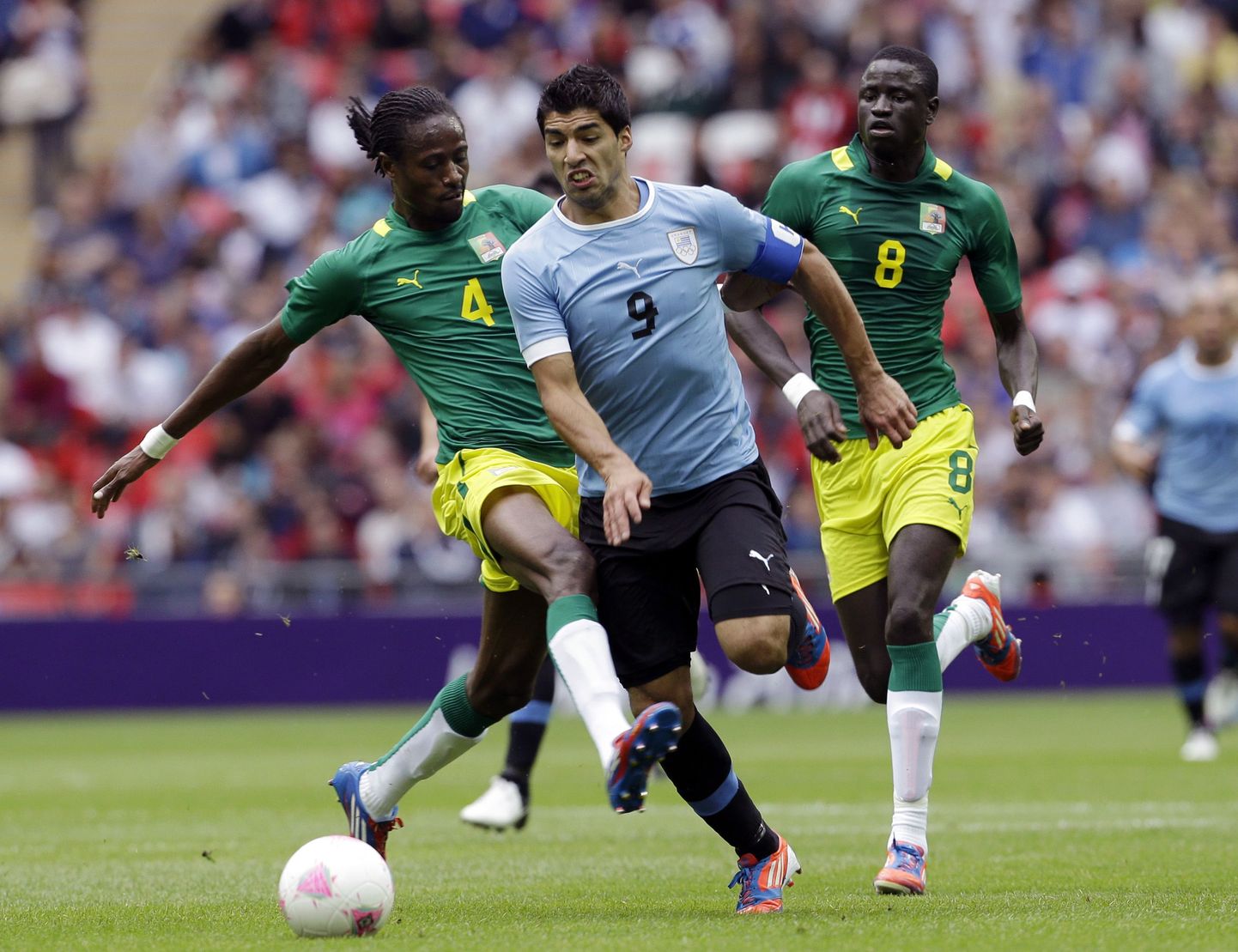 Uruguay's Luis Suarez (9) is tackled by Senegal's Abdoulaye Ba (4) as Senegal's Cheikhou Kouyate (8) watches, resulting in a red card for Ba during a men's first-round group A soccer match at the 2012 Summer Olympics, Sunday, July 29, 2012, at Wembley Stadium in London. (AP Photo/Ben Curtis) / SCANPIX Code: 436