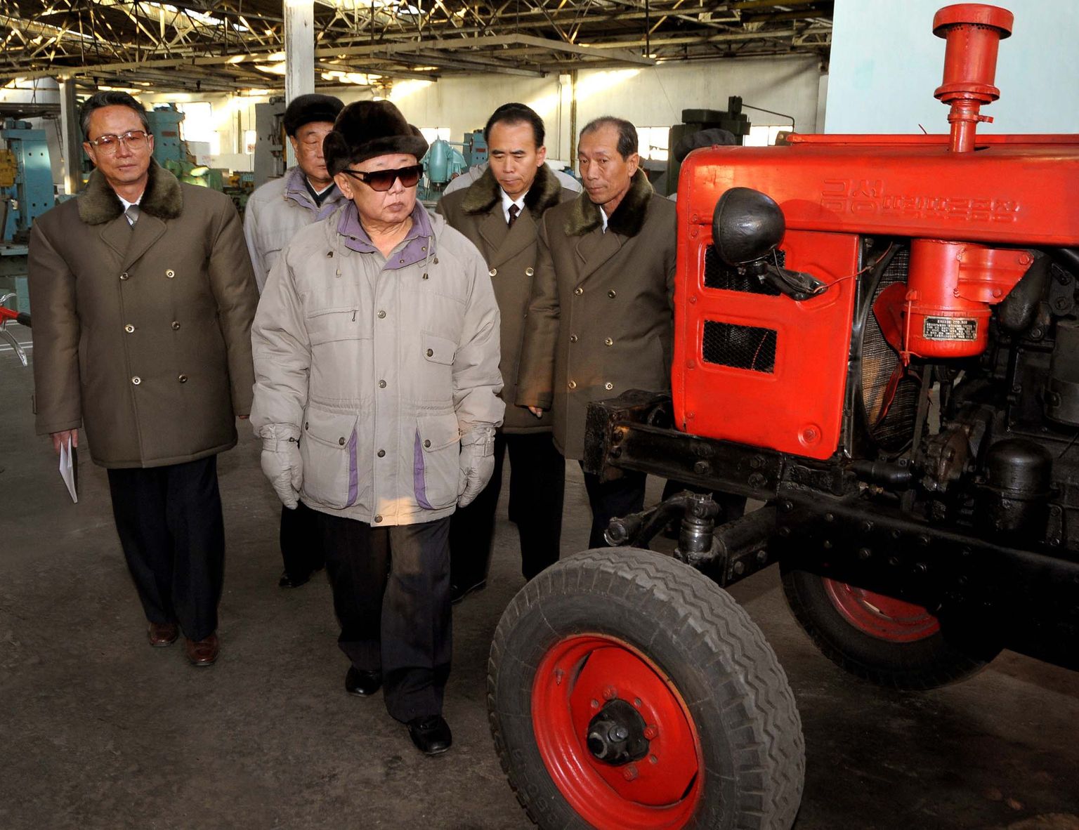Kim Jong-il (keskel) Põhja-Korea Kumsongi traktoritehases, mille asukohta pole avaldatud. Ka pole teada kuupäev, mil foto tehti.