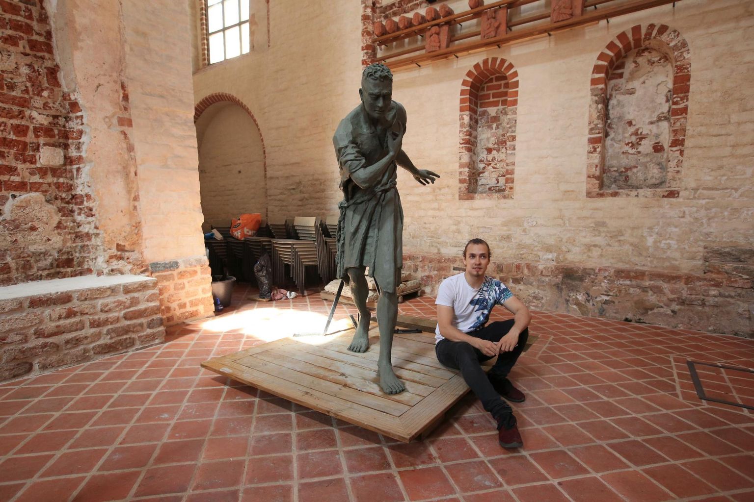Kahrut-Silvester Vilbaste istub oma skulptuuri «Ma luban, et ma tulen tagasi» alusel Jaani kirikus.