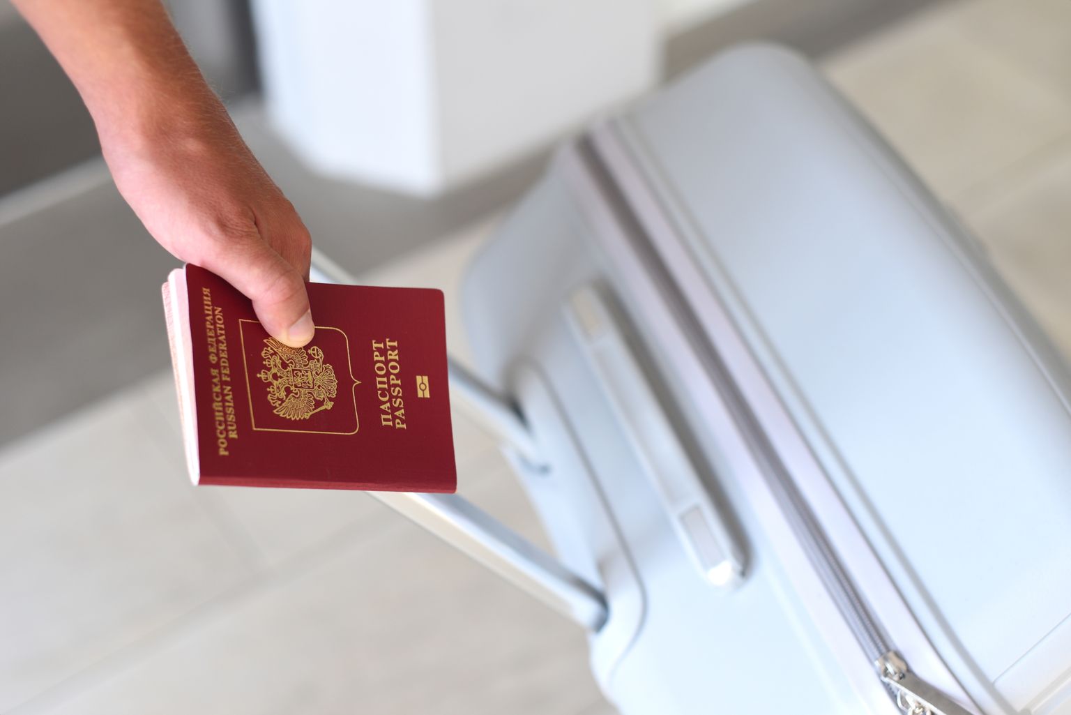 Vene Föderatsiooni passi ja reisikohvriga inimene. Pilt on illustreeriv