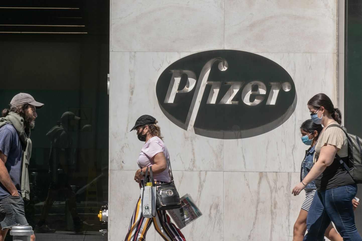 Maskides jalakäijad möödumas Pfizeri peakorterist New Yorgis 22. juulil 2020, mil Pfizer ja Saksa biotehnoloogiafirma BioNTech allkirjastasid USA valitsusega ligi kahe miljardi dollari suuruse lepingu 100 miljoni doosi koroonaviirusevastase vaktsiini tootmiseks aasta lõpus.