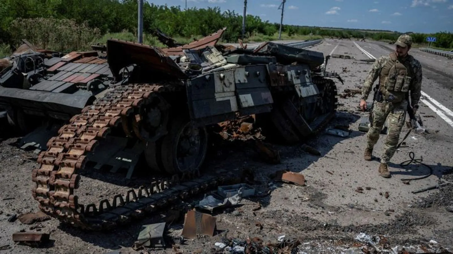 Украинский военный рядом с подбитым танком.