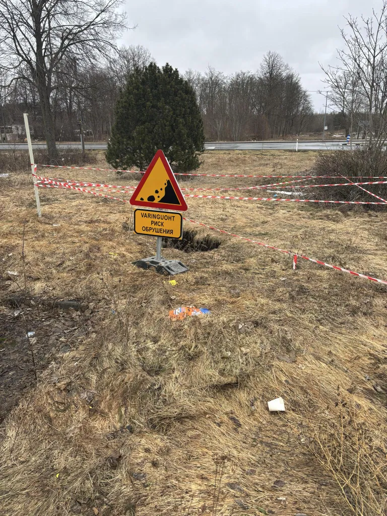 Помимо предупреждающей ленты, вокруг провала установлены знаки, предупреждающие о риске обвала.