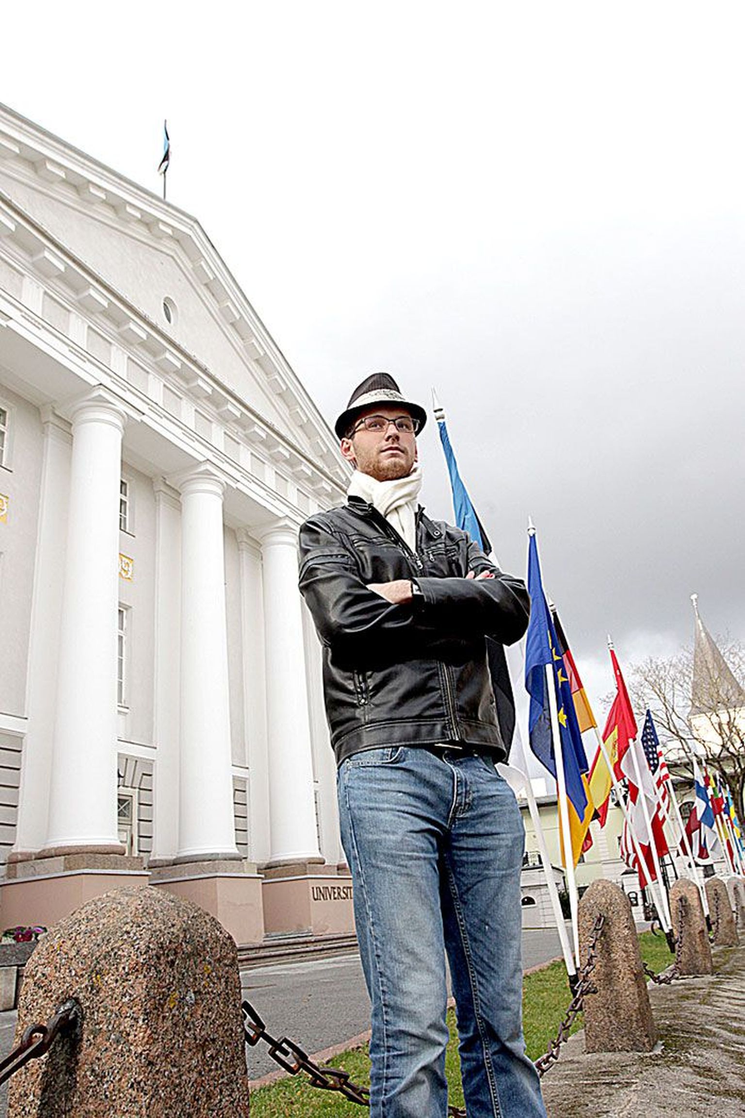 Jonas Tarm seisab Tartu ülikooli peahoone ees. Samas majas tuleb täna kell 19 algaval kontserdil maailmas esimest korda ettekandele tema kooritsükkel «Peegelpildid».