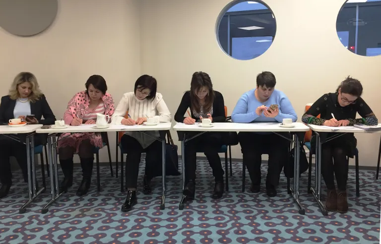 Moldovlased täidavad tagasisidelehti, kasutades telefoni abi tõlkimisel. Vasakul Moldova suursaadik Eestis Inga Ionesii. Roosa õlasalliga naine on sterilisatsiooniosakonna vanemõde Tatiana Stratan, tema kõrval haigla ülemõde Olga Pinteac, siis Svetlana Vozian, Nadejda Calestru ning nakkusarst Ana Argint, kelle õlul hakkab olema infektsioonikontrolli teenistuse loomine.