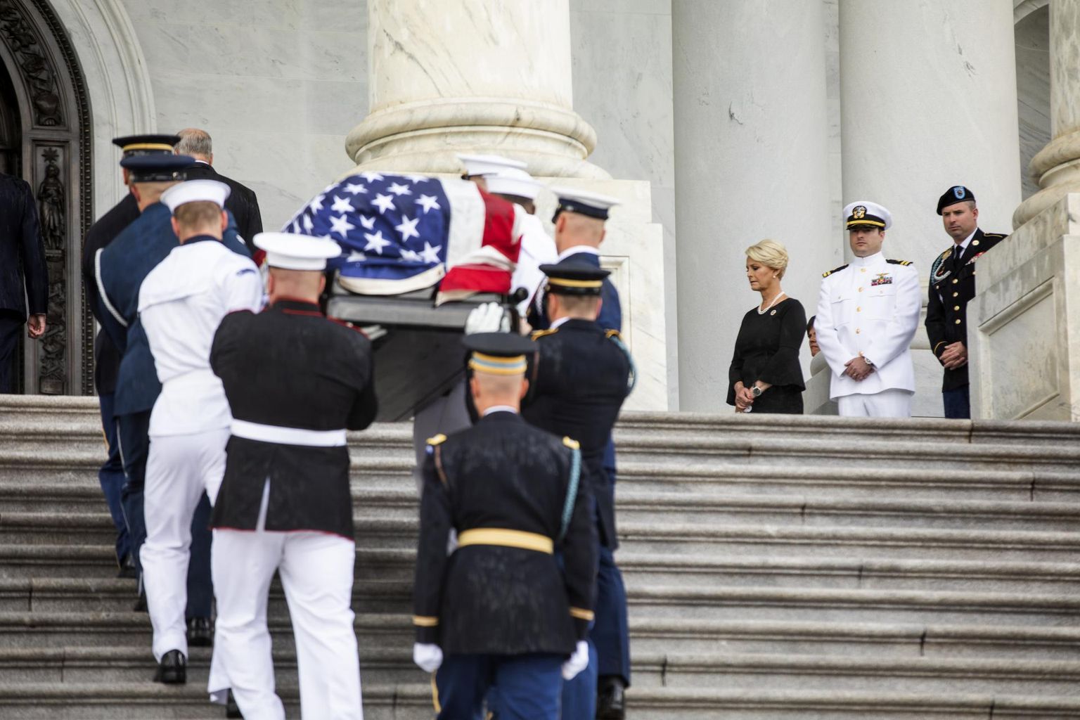 Sõjaväelased kandmas John McCaini sarka Washingtoni Kapitooliumi rotundi. Üleval ootavad lesk Cindy McCain ja pojad Jack ja James.