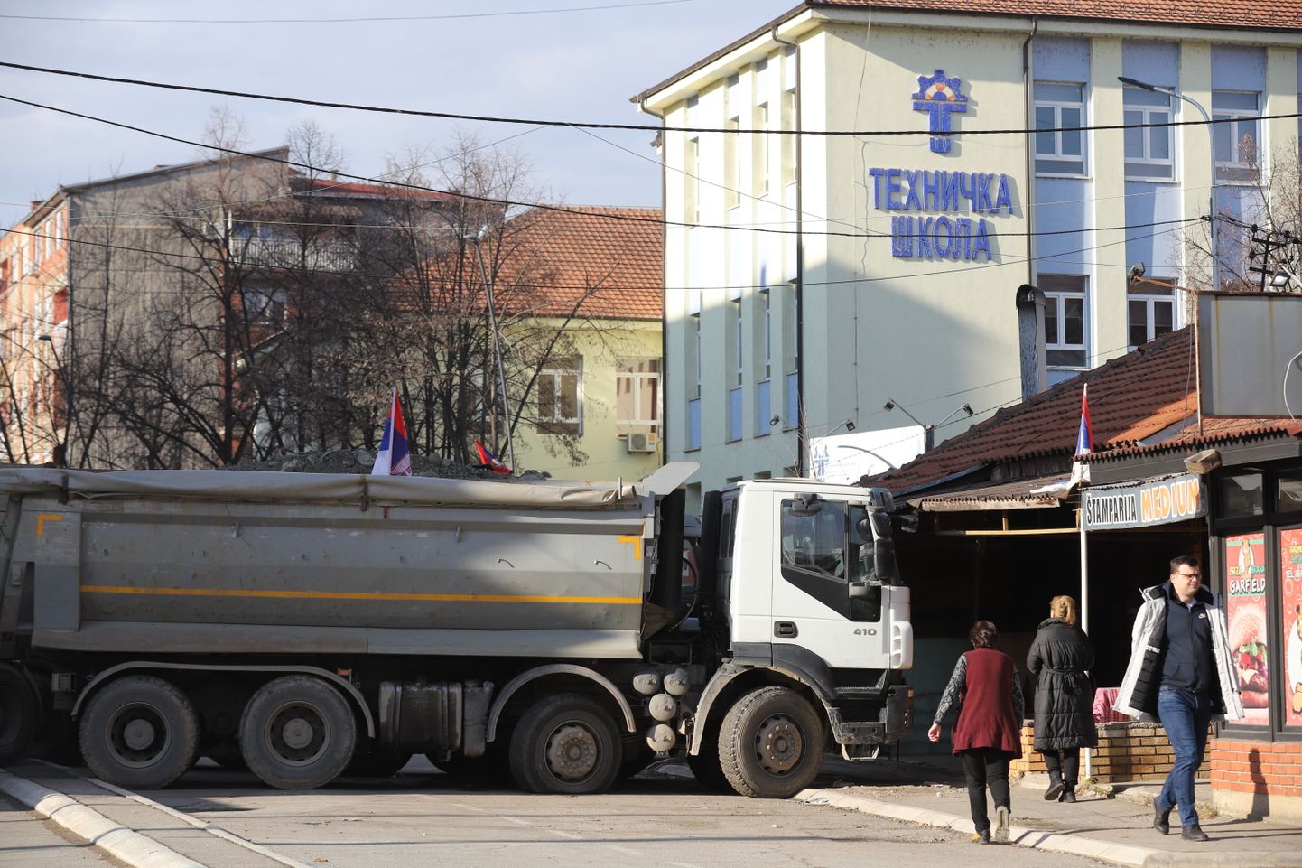 Жители проходят мимо грузовиков, блокирующих дорогу в северной части Митровицы, Косово, 29 декабря 2022 года.