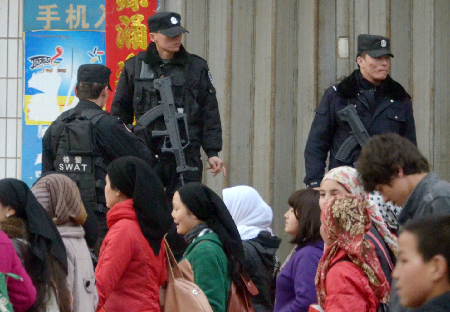 Uiguurid mööduvad Hiina politseinikest.