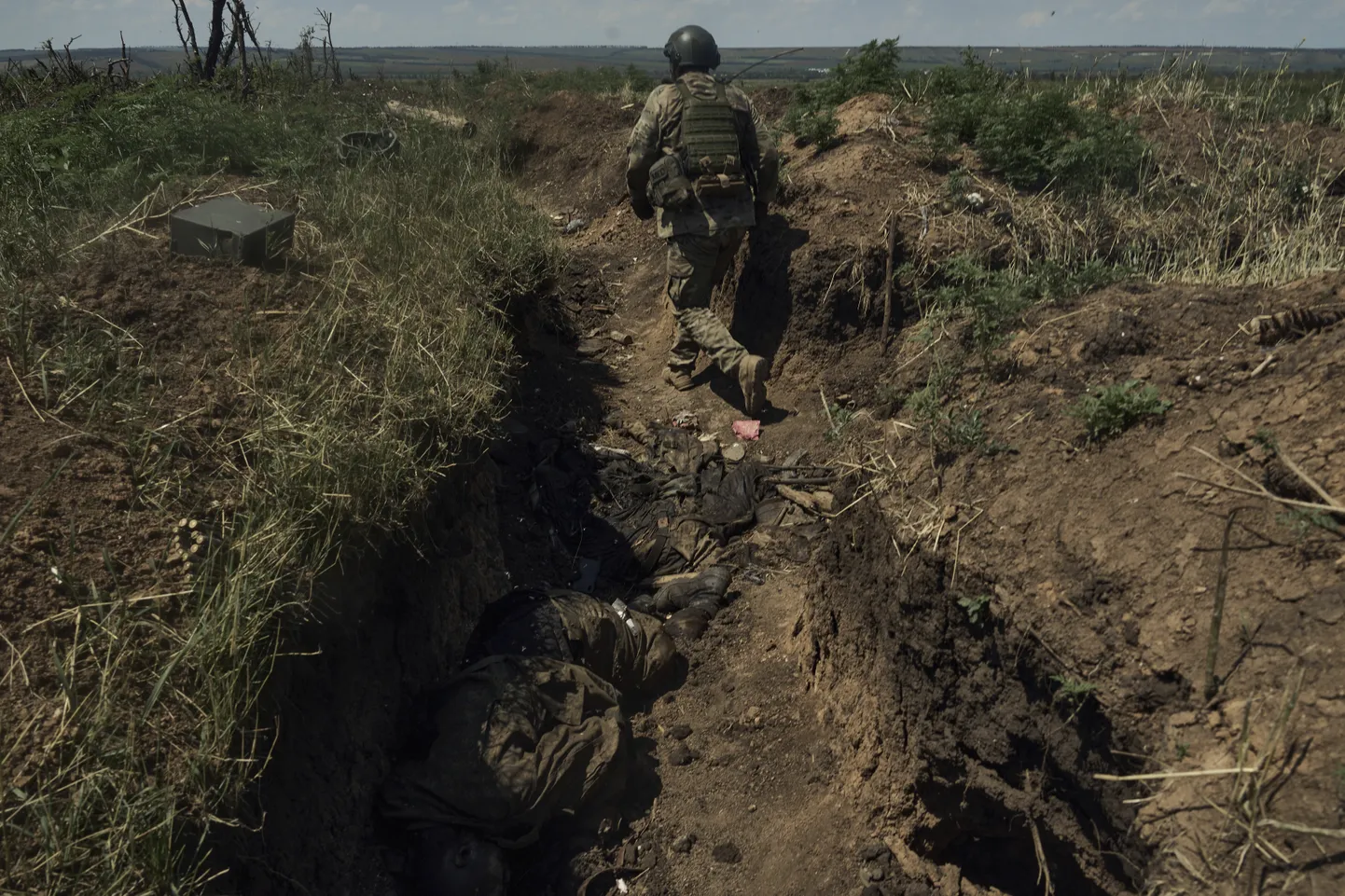 Ukrainas karavīrs iet pa ierakumiem Doneckas apgabalā, kuros ir okupantu līķi