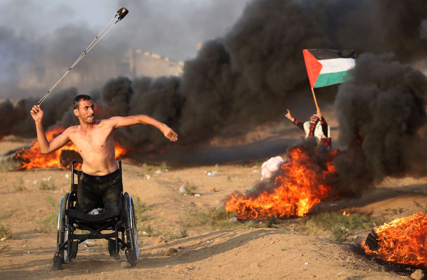 Palestīniešu protestētājs ratiņkrēslā met akmeņus Izraēlas armijas virzienā