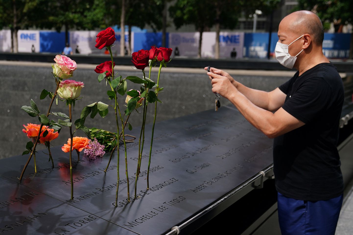 Мужчина фотографирует цветы у Национального мемориала жертвам 9/11 за день до 19-й годовщины терактов в районе Манхэттена Нью-Йорк