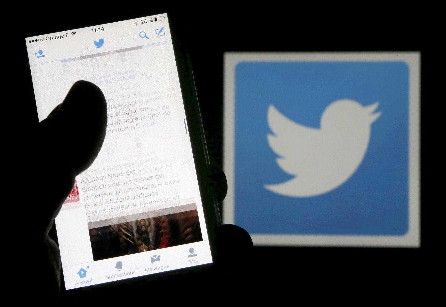 FILE PHOTO: A man reads tweets on his phone in front of a displayed Twitter logo in Bordeaux, southwestern France, March 10, 2016.  REUTERS/Regis Duvignau/Illustration/File Photo