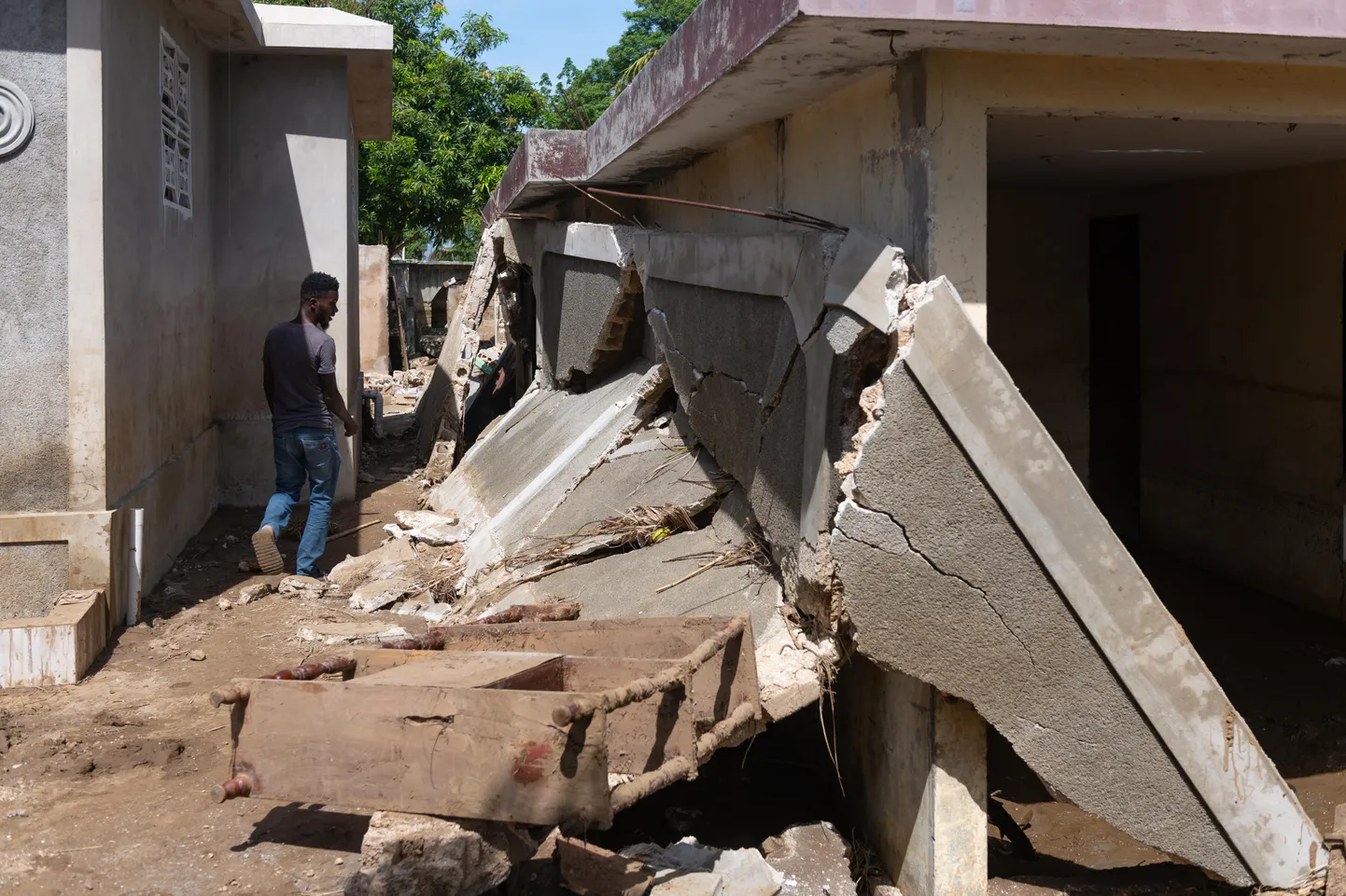 Mees kõndimas Haiti maavärinas kannatada saanud maja rusude kõrval.