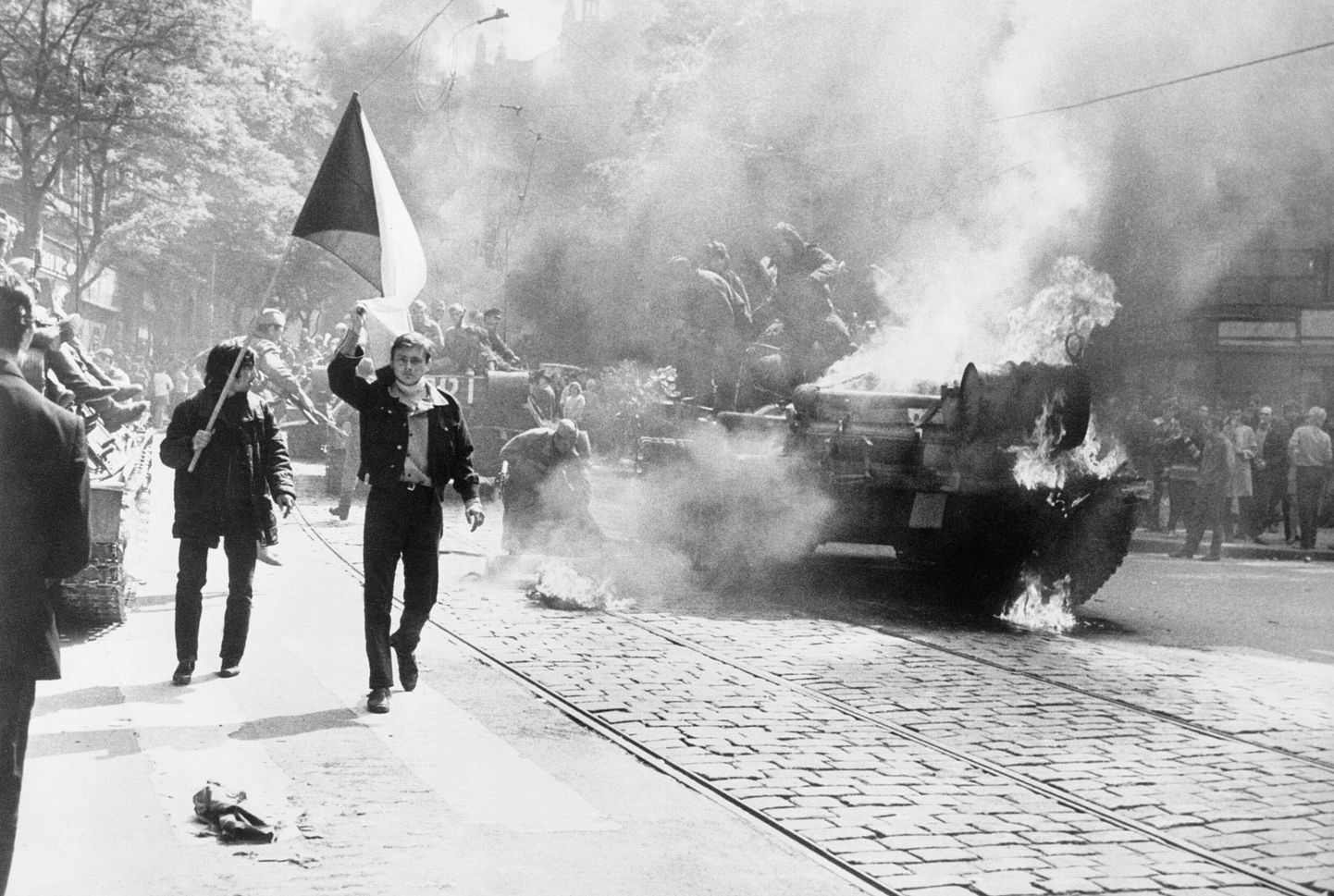 Tšehhoslovakkia elanikud, kandes oma maa rahvuslippu, mööduvad põlevast tankist Prahas Nõukogude sissetungi ajal.