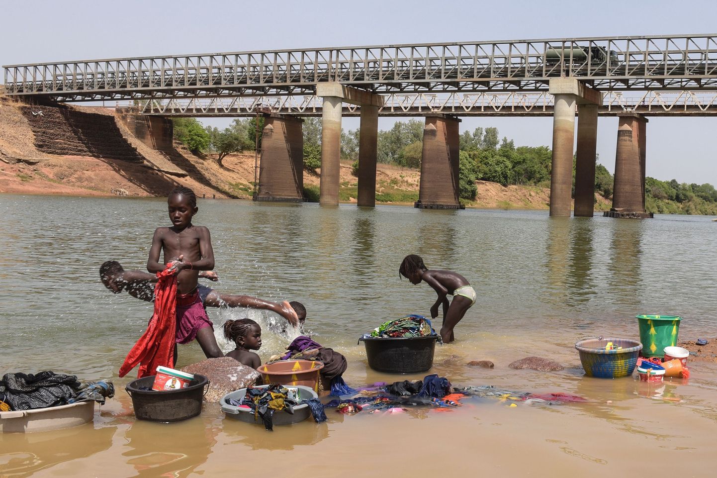 Senegali lapsed Gouloumbou jõe ääres ennast ja oma riideid loputamas. Nende vanemad peavad samal ajal jõehobuvalvet.