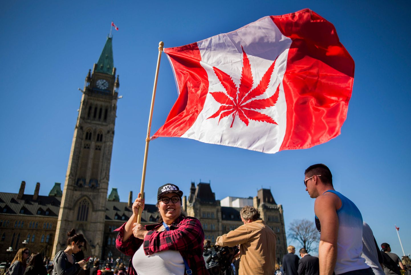 Naine lehvitamas Kanada lippu, millel on vahtraleht asendatud kanepilehega.