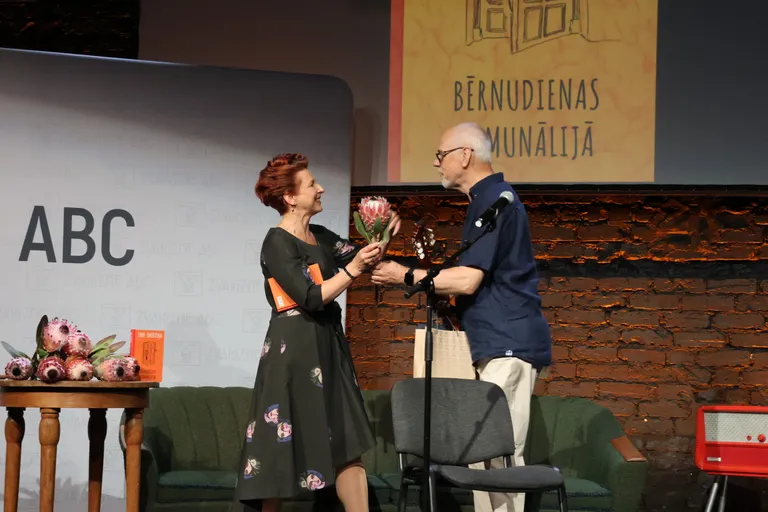 Zani Daudziņu sveic ģitārists un komponists Aivars Hermanis, kurš grāmatas atklāšanas vakara viesus priecēja ar melodiskām starpspēlēm.