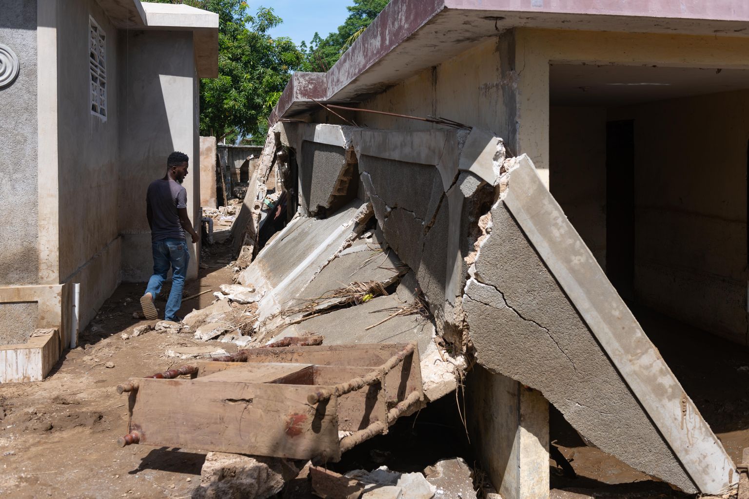 Mees kõndimas Haiti maavärinas kannatada saanud maja rusude kõrval.