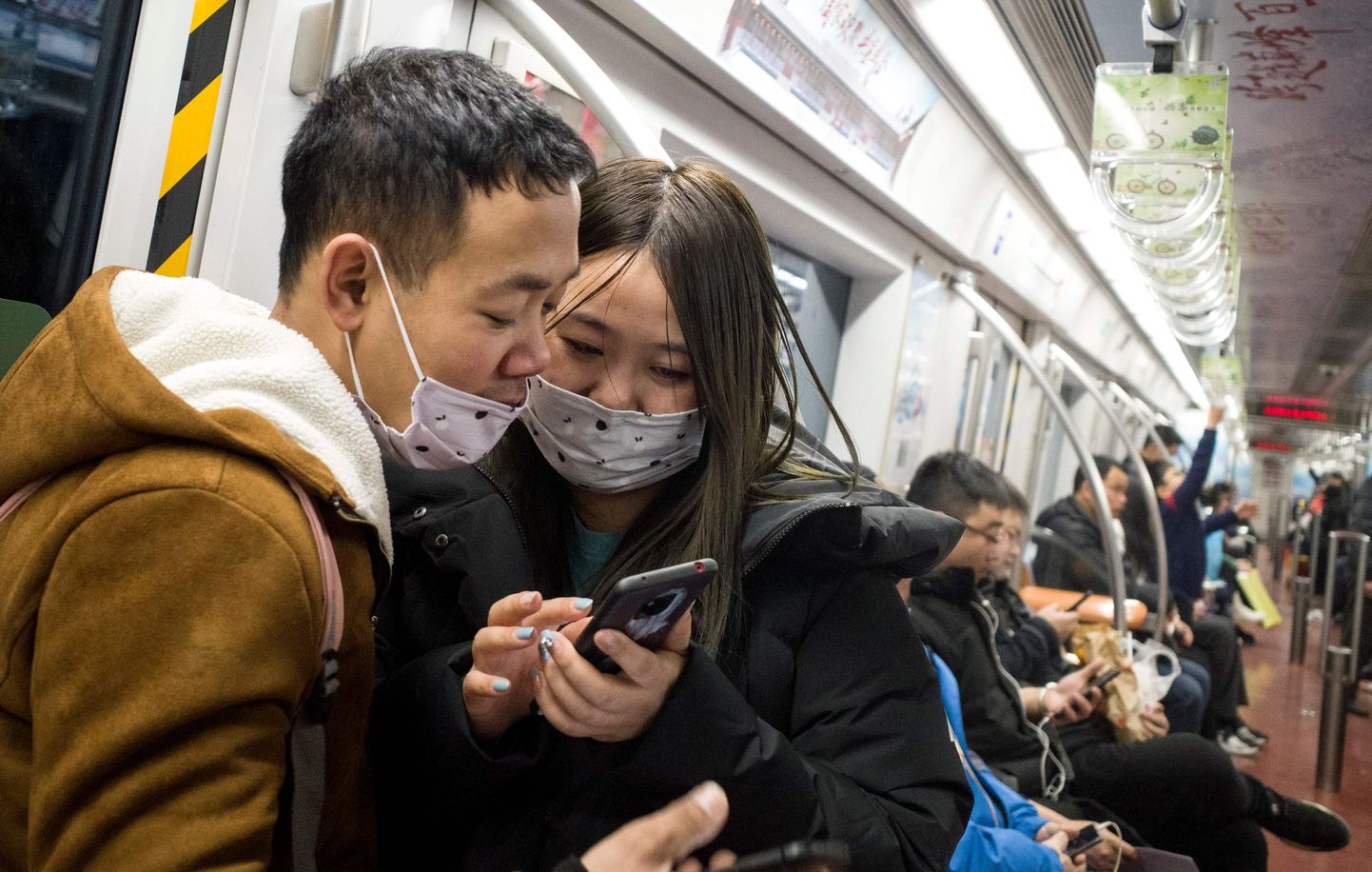 Subway passengers wear protective masks in Beijing on January 21, 2020. - The death toll from a new China virus that is transmissible between humans rose to six, the mayor of Wuhan said in an interview with state broadcaster CCTV on January 21, as the World Health Organization said it would consider declaring an international public health emergency over the outbreak. (Photo by NOEL CELIS / AFP)